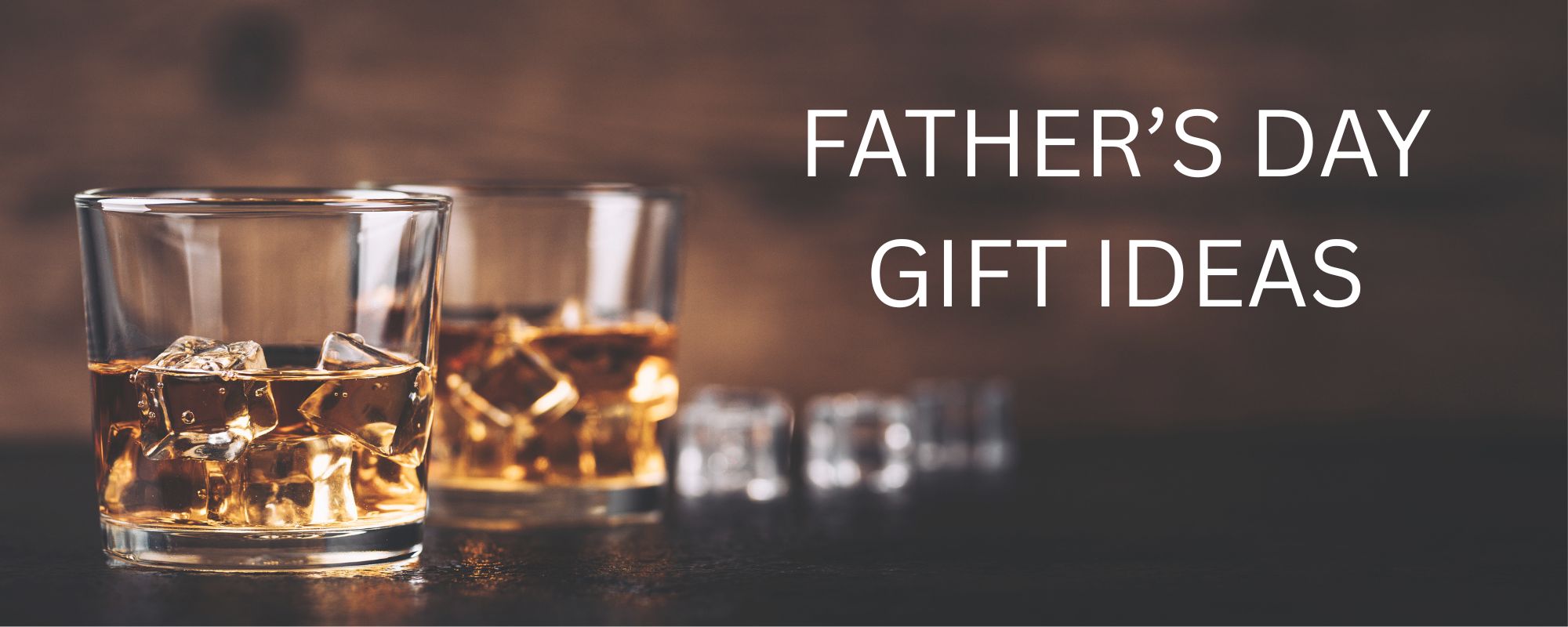 Two clear whiskey glasses filled with amber liquor and ice on a dark wooden surface, with the text 'FATHER'S DAY GIFT IDEAS' in white on the right side.